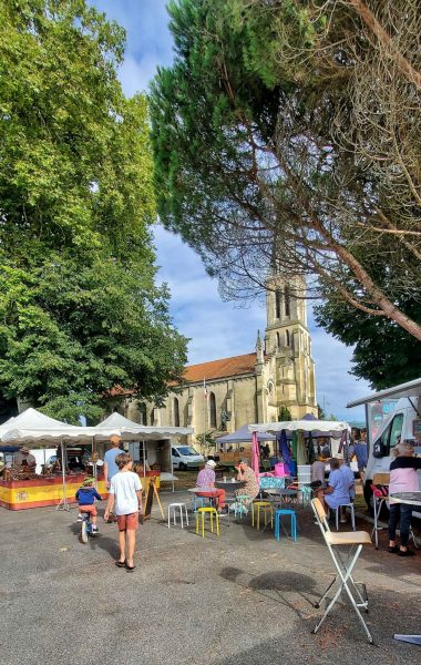 photo verticale du marché de le porge avec l'église en fond