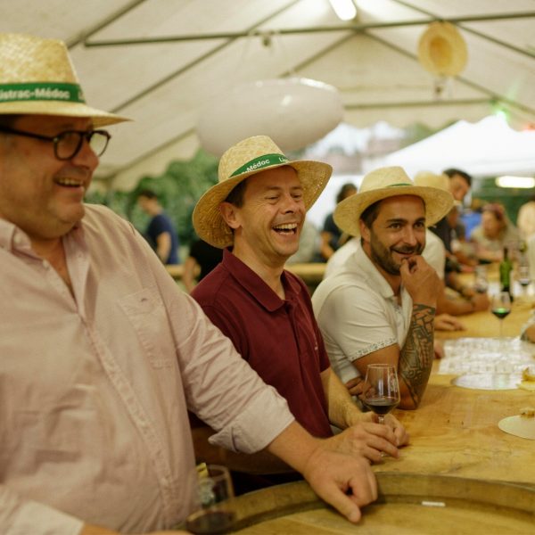 Viticulteurs sous un barnum en train de rire et servir des festivaliers