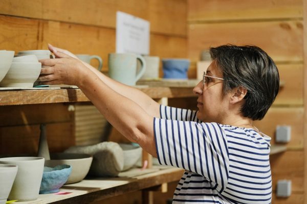 Laurence de profil qui attrape une poterie sur une étagère en hauteur