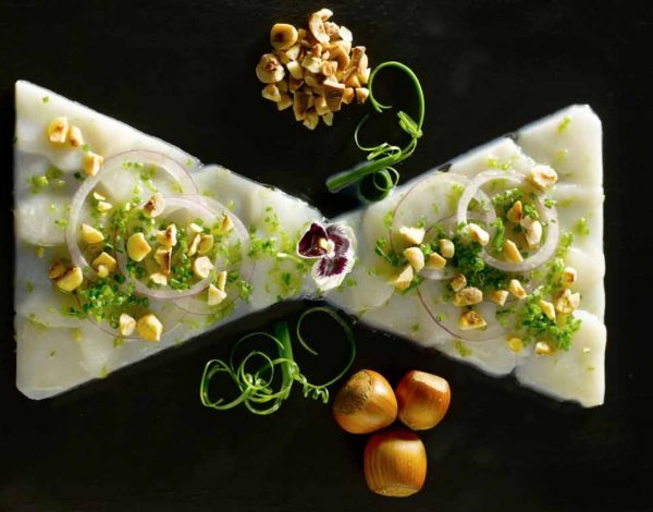 Photo d'un carpaccio de saint jacques et noisette torréfiées en forme de noeud de papillons