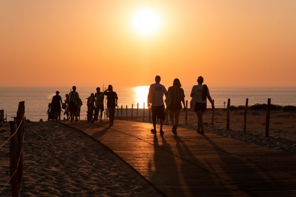 personnes se dirigeant vers l'océan pour voir le coucher du soleil au porge océan