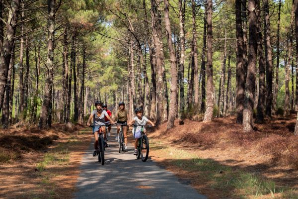famille de face faisant du vélo sur piste cyclable du Porge en gironde