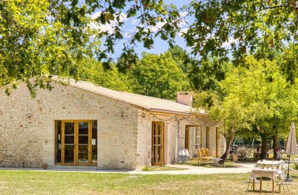 batisse en pière de loin avec des feuille et branche d'arbre au premier plan