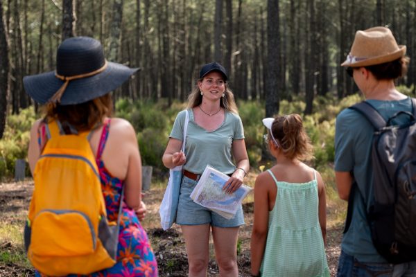 une guide naturaliste de face en arrière plain et des touristes de dos écoutant ses explications au premier plan