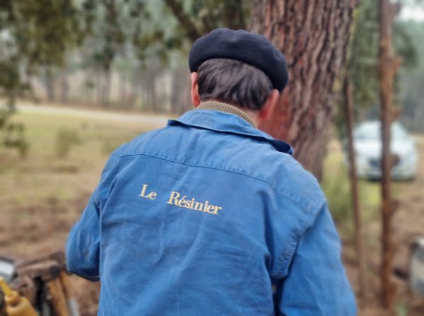 Homme de dos avec un bleu de travail avec écrit "le résinier" dessus